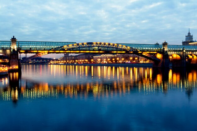 Photo illuminated bridge over river against sky in city