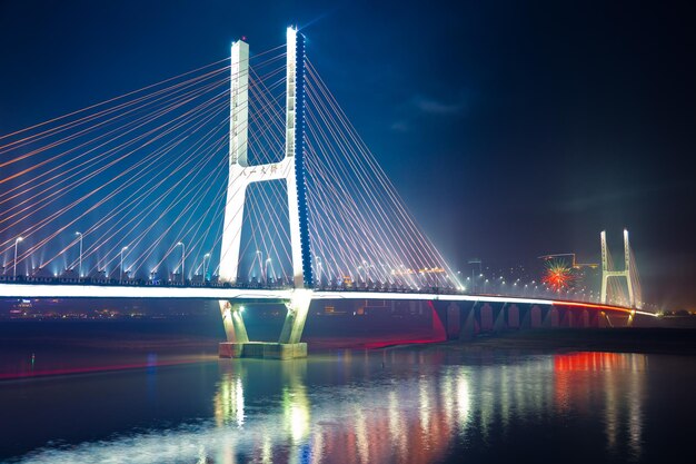 Illuminated bridge over river against sky at night