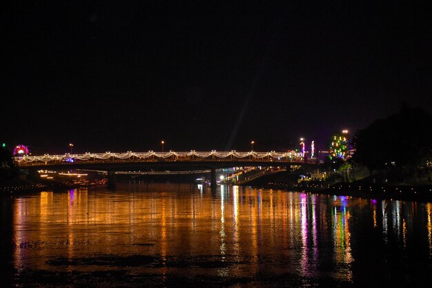 Illuminated bridge over river against sky at night