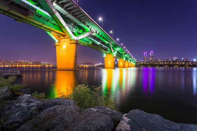 Photo illuminated bridge over river against sky at night