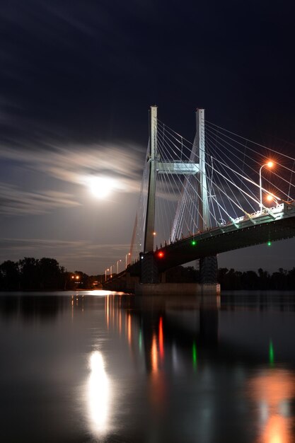 Photo illuminated bridge over river against sky at night