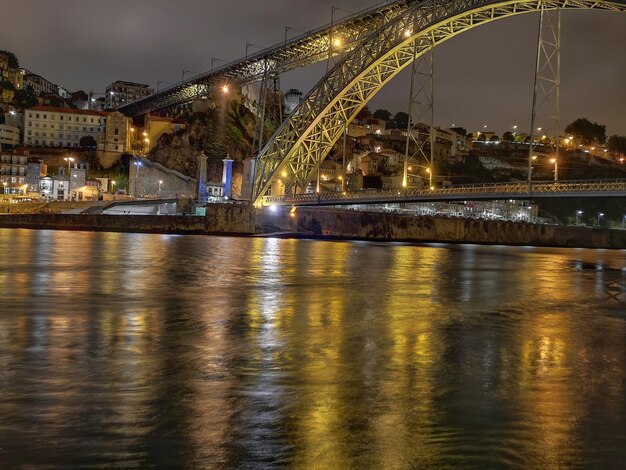 Foto ponte illuminato sul fiume contro il cielo notturno