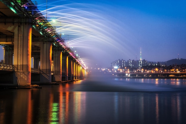 illuminated bridge over river against sky at night