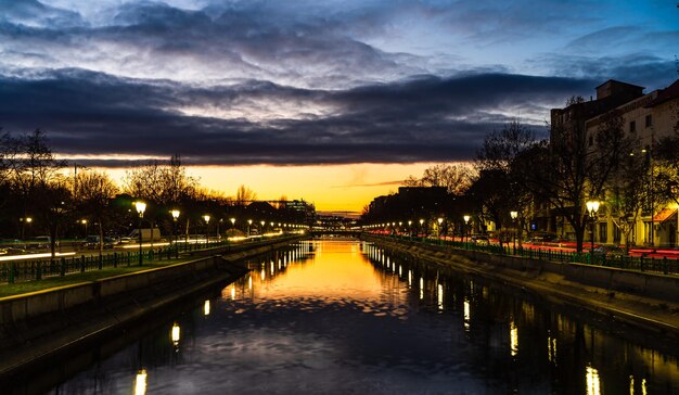 Illuminated bridge over river against sky at sunset