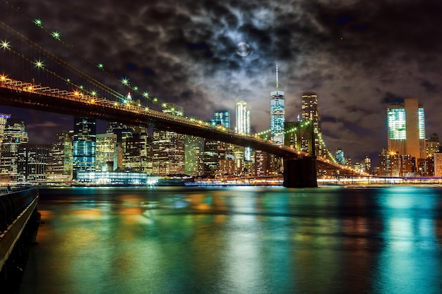 illuminated bridge over river by city at night