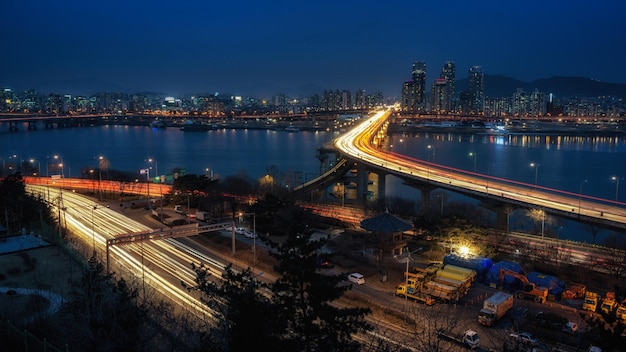 Illuminated bridge over river in city at dusk