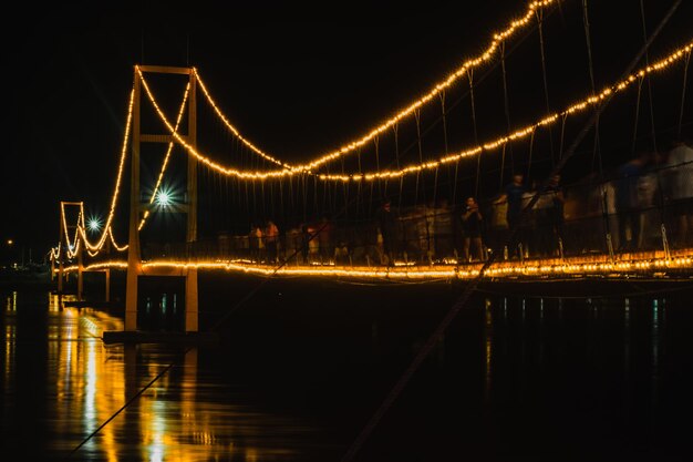 Foto ponte illuminato sul fiume di notte