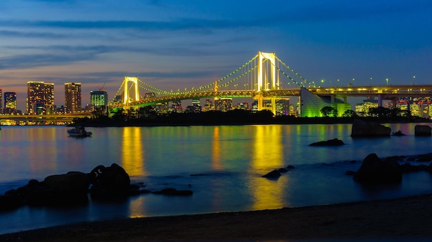 Illuminated bridge over river with city in background