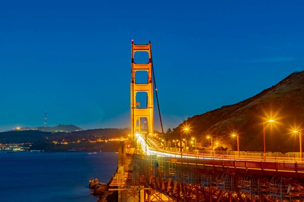 Illuminated bridge over sea against blue sky