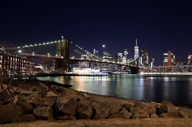 illuminated brooklyn bridge over river at night