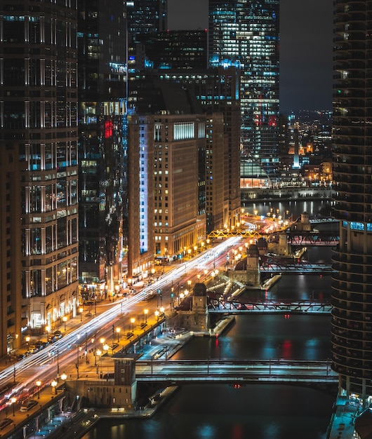 Illuminated buildings by bridges over river in city at night