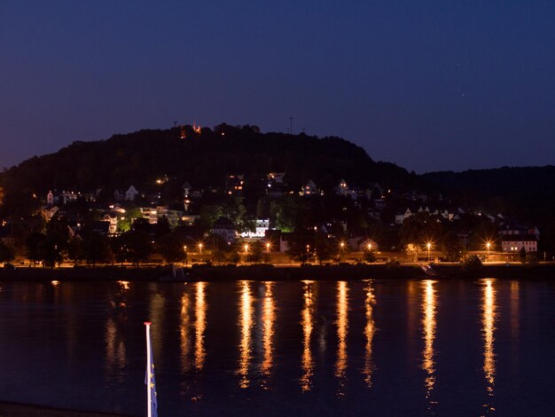 Photo illuminated buildings by lake against clear sky at night