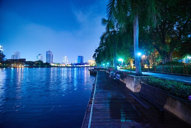 Illuminated buildings by river against sky at night