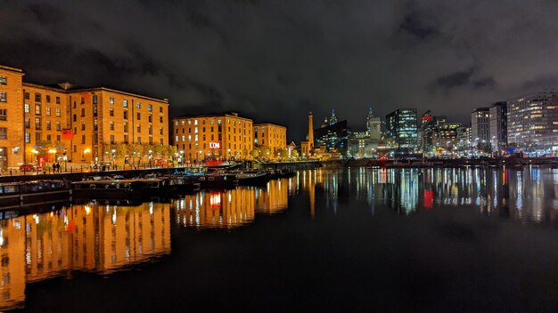 Illuminated buildings by river against sky at night