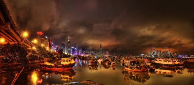 Illuminated buildings by river against sky at night