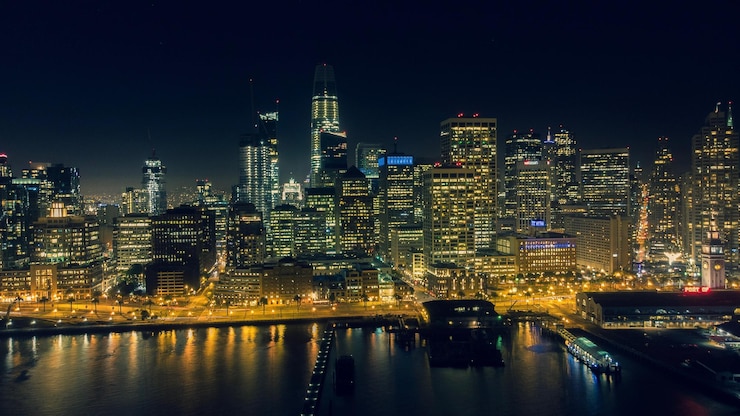 Photo illuminated buildings by river against sky at night