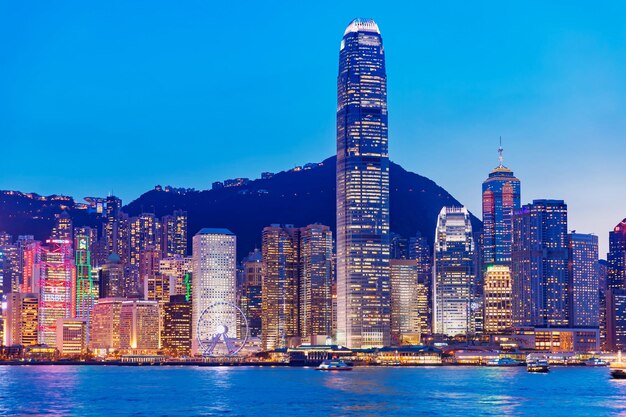 Photo illuminated buildings in city against blue sky