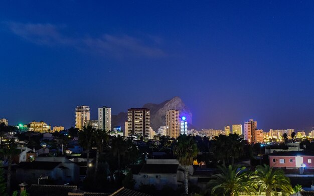 Illuminated buildings in city against clear blue sky