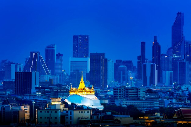 Photo illuminated buildings in city against sky at dusk