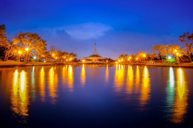 Illuminated built structure by lake against sky at night