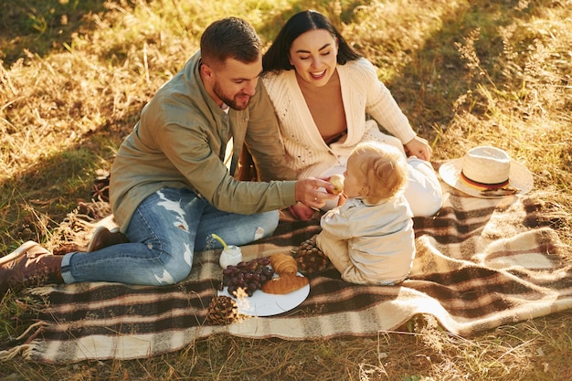 Illuminated by sunlight Happy family of father mother and little daughter is in the forest