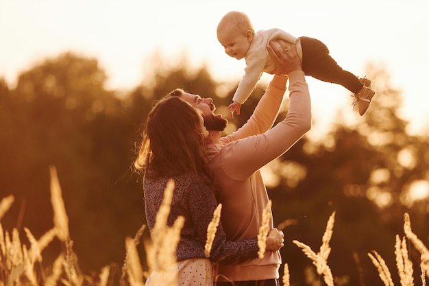 Illuminated by sunlight Happy family of mother family and little baby rests outdoors Beautiful sunny autumn nature