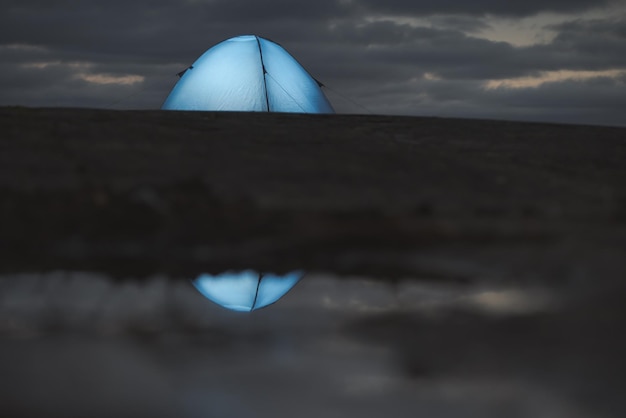 Illuminated camping tent against a beautiful sky