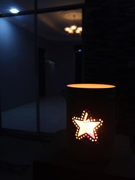 Photo illuminated candle in container at home