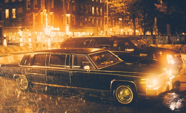 夜の雨季の通りで照らされた車