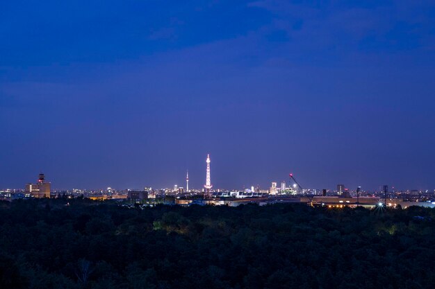 Illuminated city against clear blue sky at night