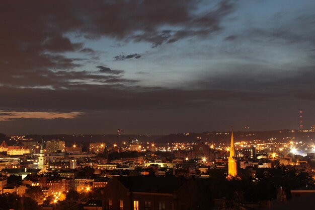 Photo illuminated city against cloudy sky at sunset