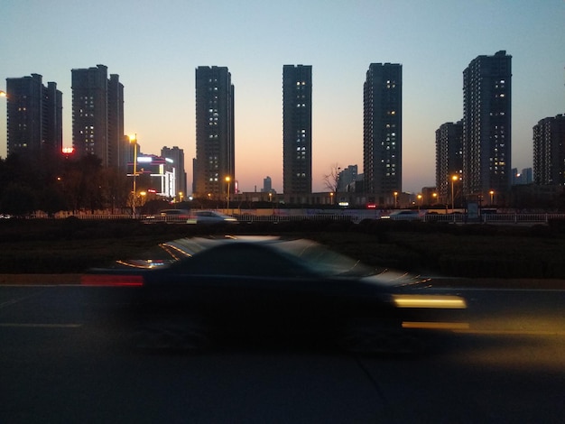 Photo illuminated city by buildings against sky at night