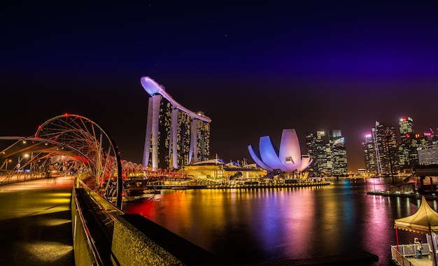 illuminated city by river against sky at night