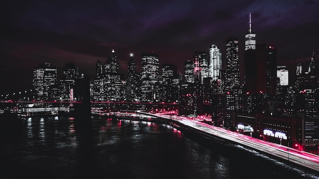 Photo illuminated city by river against sky at night