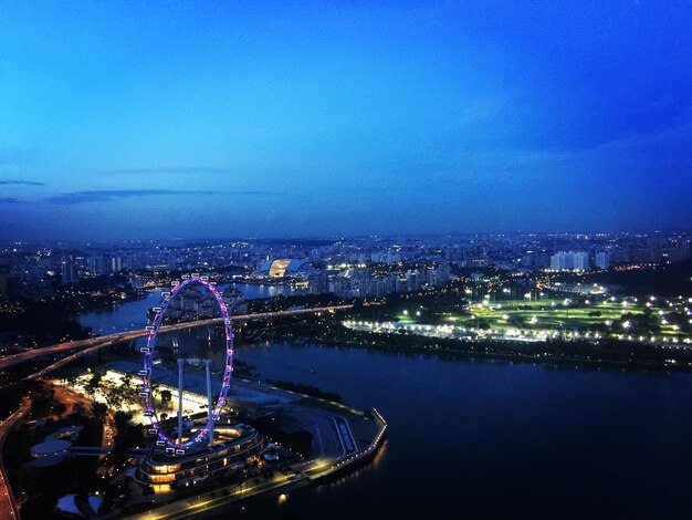 Illuminated city by river against sky at night