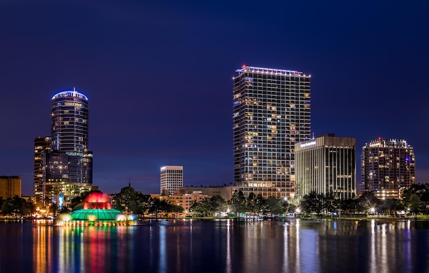 Photo illuminated city by river against sky at night