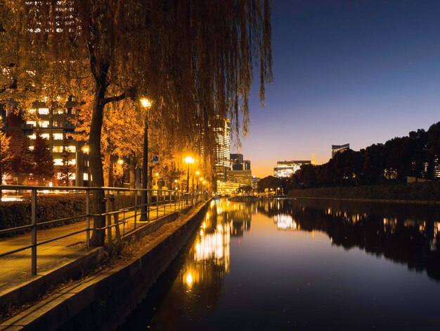 Illuminated city by river against sky at night