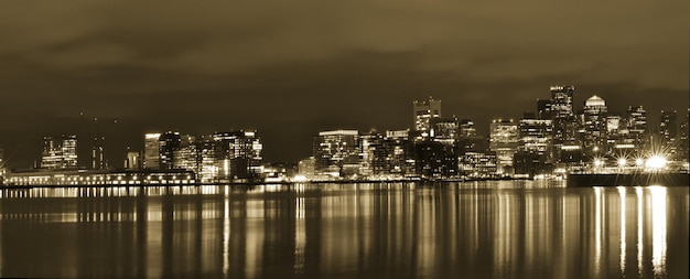 Photo illuminated city by river against sky at night