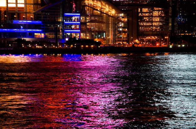 Photo illuminated city by river against sky at night