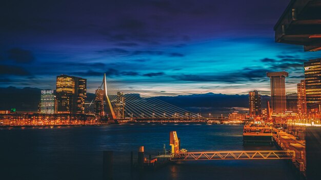 Illuminated city by sea against sky at night