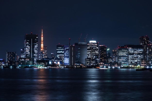 Photo illuminated city by sea at night