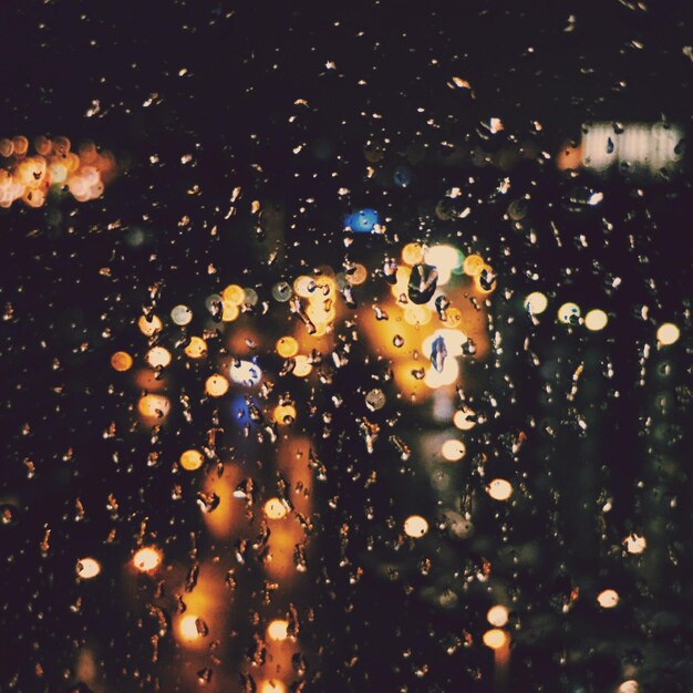 Illuminated city seen through wet glass during monsoon