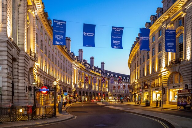 Illuminated city street and buildings against sky at dusk