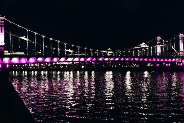 Освещенный Крымский Крымский мост ночью с отражением воды Москва