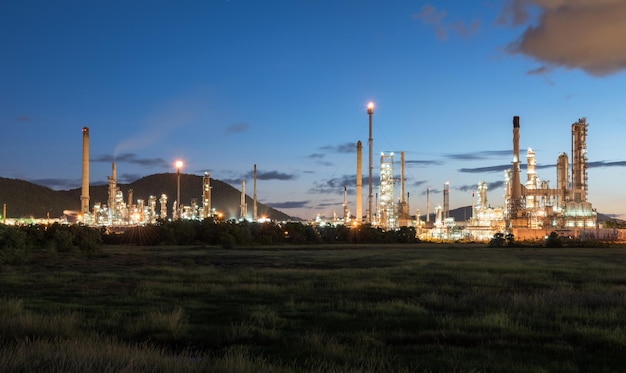 Photo illuminated factory by field against blue sky