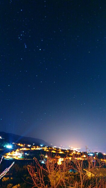 Illuminated ferris wheel against blue sky at night