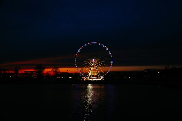 Photo illuminated ferris wheel against sky at night