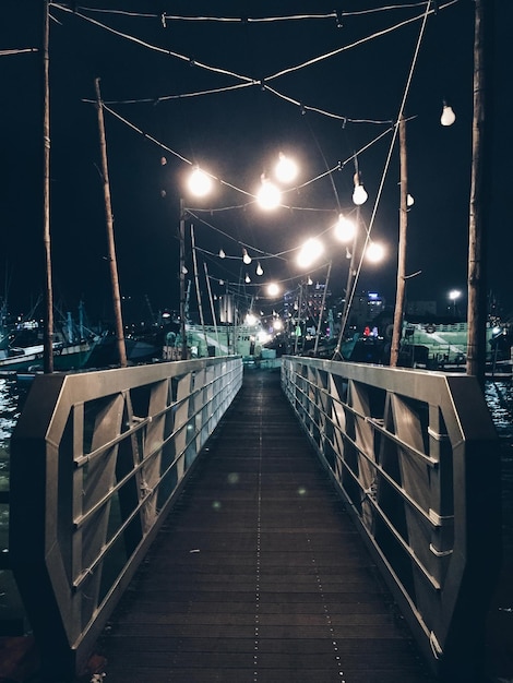 Photo illuminated footbridge over street at night