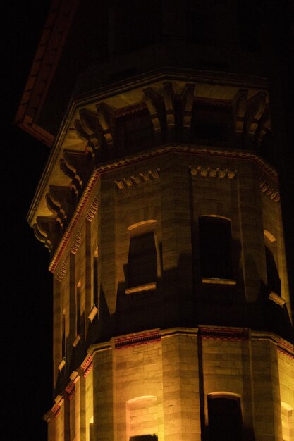 Photo illuminated from below a large stone tower in the dark