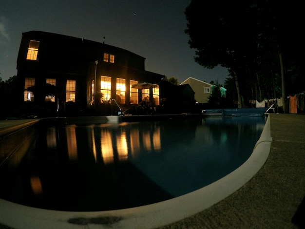 Photo illuminated house by swimming pool at night